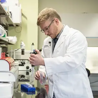 男药学系学生在实验室拿着移液器工作.