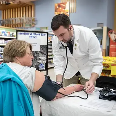 药剂师使用血压袖带和听诊器来照顾病人.