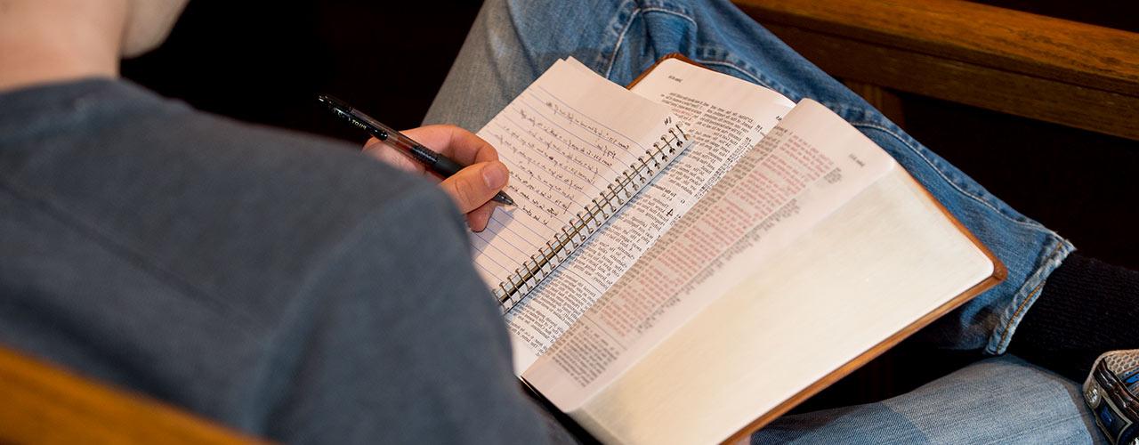 Male studies the Bible and takes notes