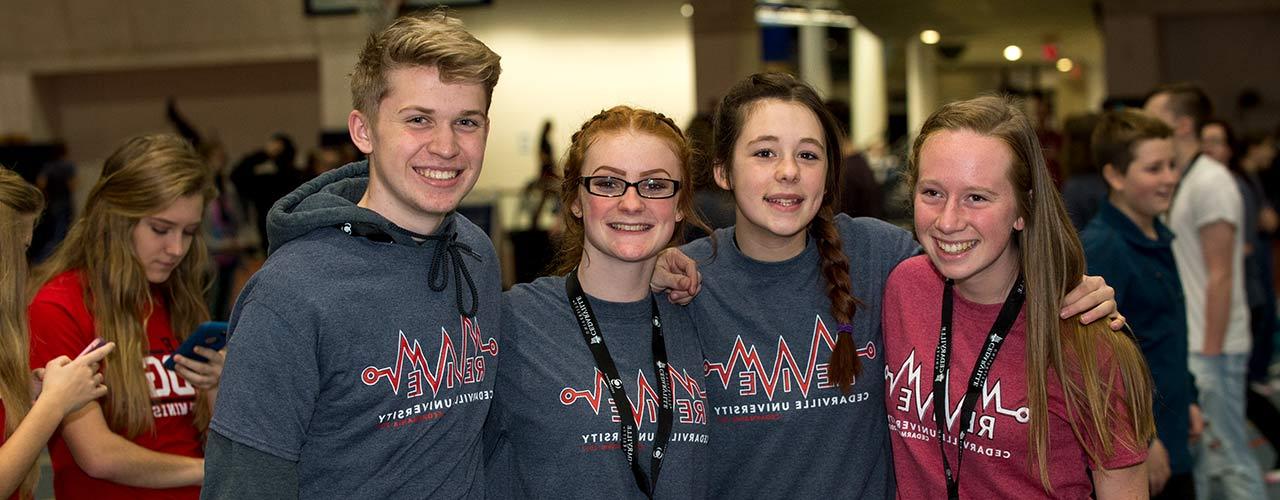 Group of students wearing lanyards smile while enjoying Cedarville's Revive event